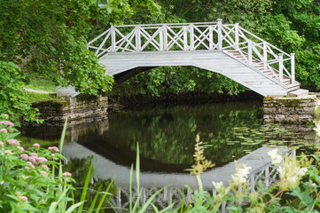 Fototapeta na wymiar Small pond and decorative white wooden bridge in park