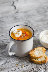 pumpkin soup with paprika in ceramic mugs on a light wooden background