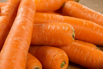 Fresh carrot with green leaves on wooden table