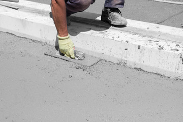 Construction worker leveling concrete pavement.