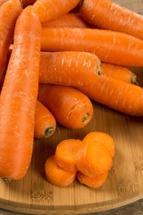 Fresh carrot with green leaves on wooden table