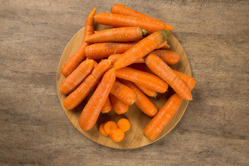 Fresh carrot with green leaves on wooden table