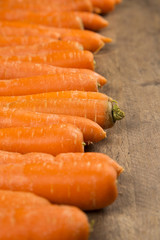 Fresh carrot with green leaves on wooden table