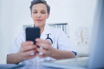 Obraz na płótnie Canvas Happy doctor using her smartphone 