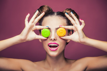 Model, a woman with bright make-up and colour biscuits joking.