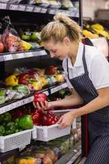 Smiling blonde worker taking a vegetables 