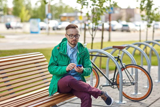 happy young hipster man with smartphone and bike