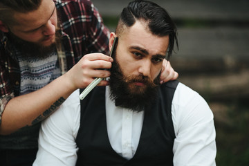 barber shaves a bearded man