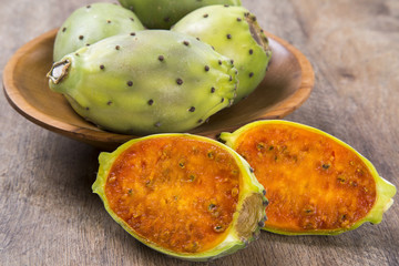 A couple of Figs of India in a wooden pot over a wooden surface.