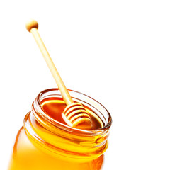 Honey in a glass jar with honey dipper isolated on white backgro