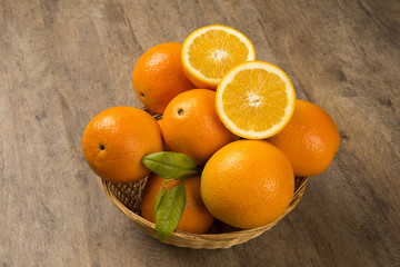 Close up of some oranges in a basket over a wooden surface