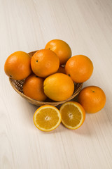 Close up of some oranges in a basket over a wooden surface