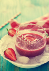 A Glass of fresh strawberry smoothie on ice cubes