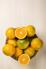 Close up of some oranges in a basket over a wooden surface