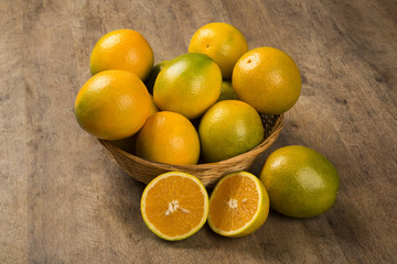 Close up of some oranges in a basket over a wooden surface