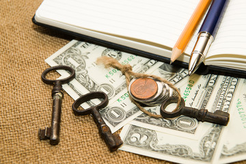 Opened notebook, pencil, pen,  key and money on the old tissue