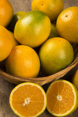 Close up of some oranges in a basket over a wooden surface