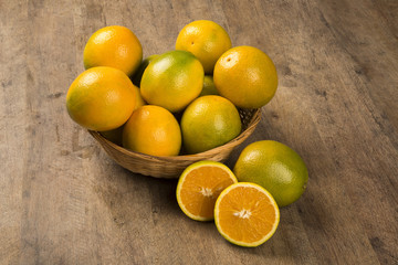 Close up of some oranges in a basket over a wooden surface