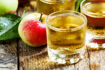 Cold apple juice and fresh apples on an old wooden table, select