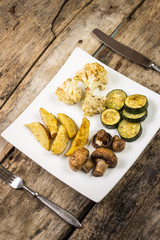 Roasted vegetables with sauce served on wooden table
