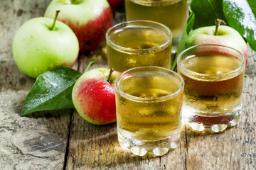 Cold apple juice and fresh apples on an old wooden table, select