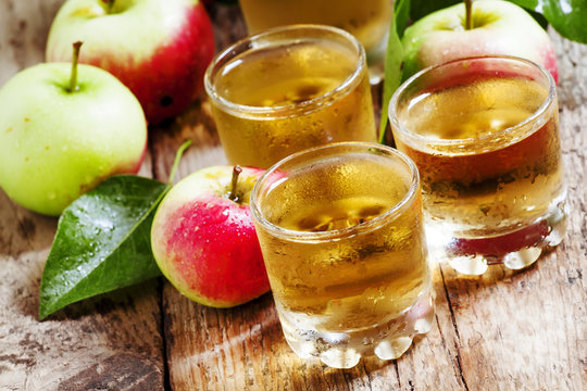 Cold apple juice and fresh apples on an old wooden table, select