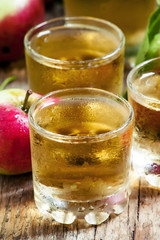 Cold apple juice and fresh apples on an old wooden table, select
