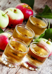 Cold apple juice and fresh apples on an old wooden table, select