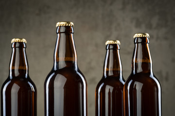 Freshly brewed beer bottles in a row over the grey concrete wall