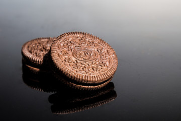 Creme-filled sandwich cookies on dark reflective background