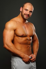 Fototapeta na wymiar Portrait of smiling muscular man on gray background