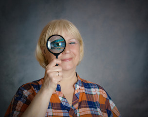 Portrait of a middle aged woman looking through a magnifying glass.