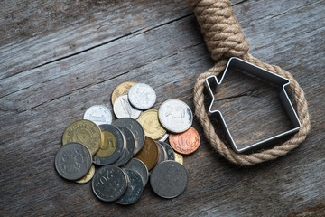 Hangman's noose with house and money on brown wooden surface