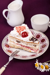 Cream cake with cherry on pink tablecloth