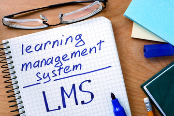 Notepad with learning management system LMS   on office wooden table.