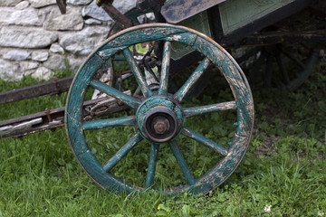 Fototapeta na wymiar Wooden wheel and hay on meadow