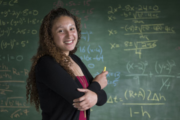 A young math teacher/student standing in front of a chalkboard