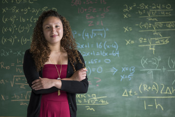 A young math teacher/student standing in front of a chalkboard