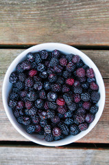 bowl full of fresh picked wild blackberries on wooden planks