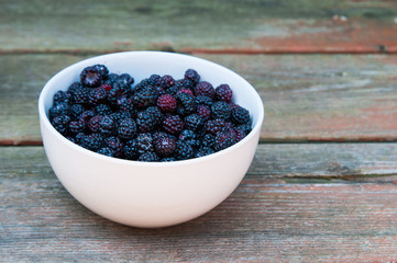 wildblackberries in a bowl with a single daisy flower