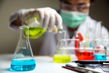 Laboratory research, lab glassware containing chemical with blur scientist 