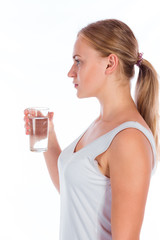 Portrait of a young happy girl holding a glass of water after fitness, isolated on a white background