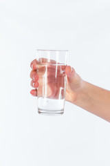 Beautiful female hand holding a glass of water, isolated on a white background