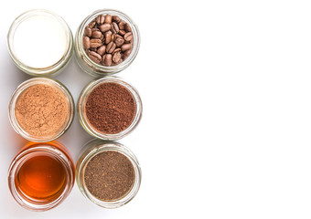 Obraz na płótnie Canvas Coffee beans, coffee powder, creamer, cocoa powder, honey and processed tea leaves in a mason jar over white background