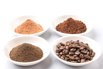 Coffee beans, powdered coffee, chocolate powder and processed tea leaves beverages in white bowl over white background