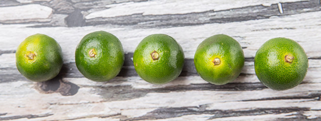 Calamansi citrus over weathered wooden background - 87091473