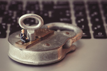 Internet security concept-miniature businessman stand on old key