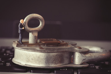 Internet security concept-miniature businessman stand on old key