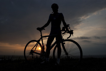 Silhouette of a biker with his bicycle at sunset