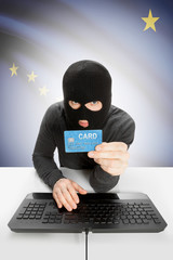 Hacker holding credit card with US state flag on background - Alaska